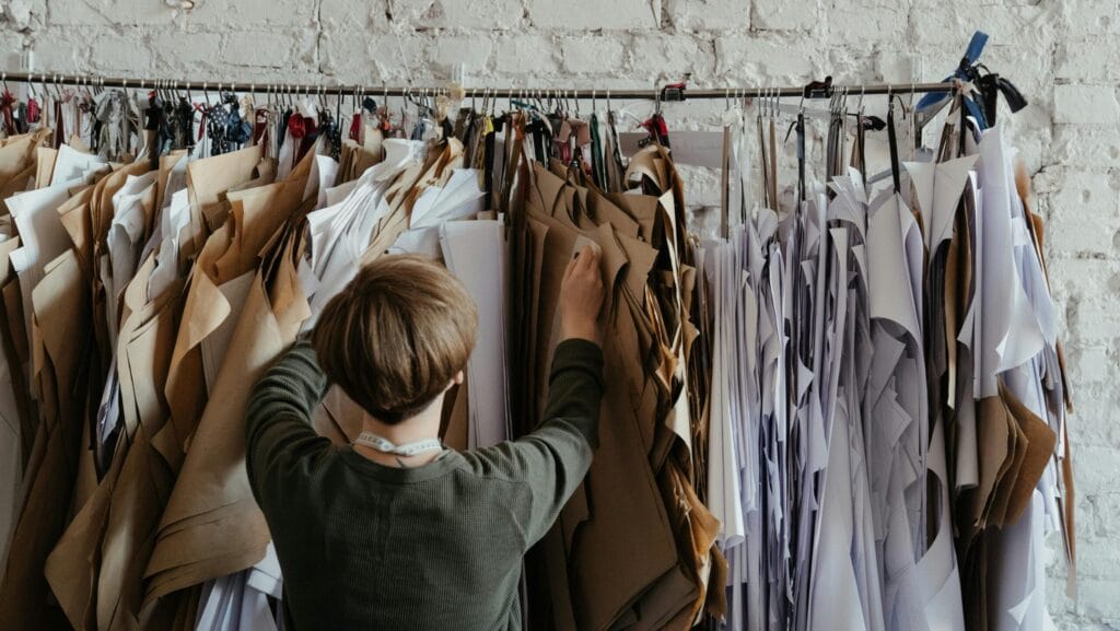 Person inspecting garment paper patterns in a fashion studio, representing apparel quality control