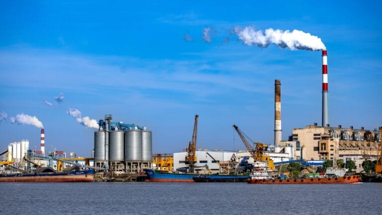 Industrial waterfront complex with cargo ships and smokestacks, representing OEM, ODM, and OBM manufacturing models