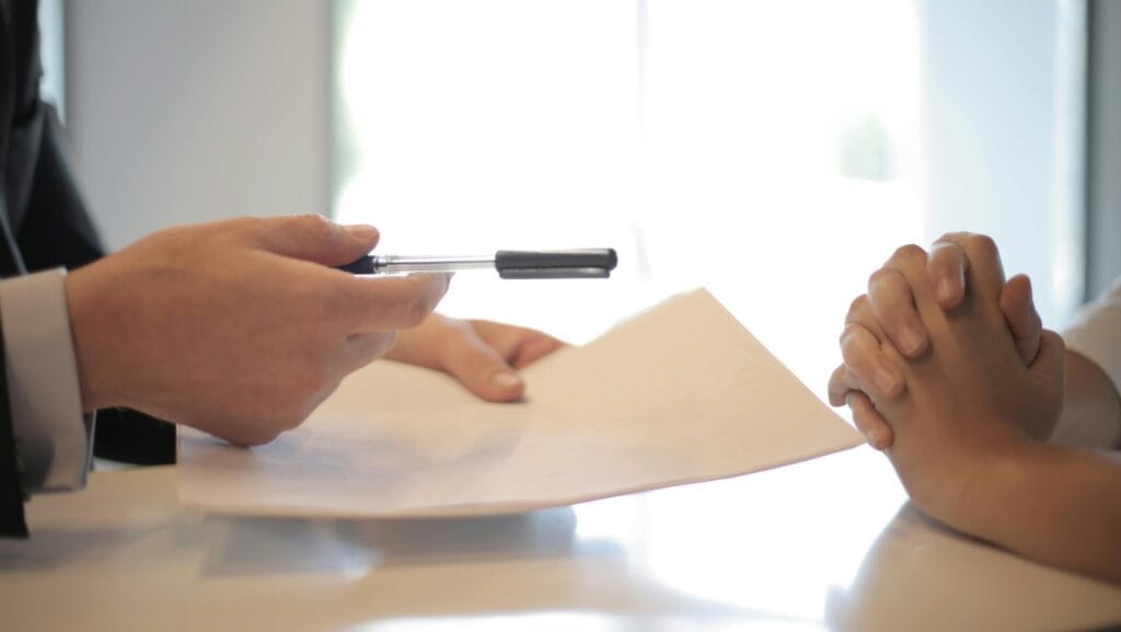 Business professionals in formal attire signing documents during FDI company setup meeting
